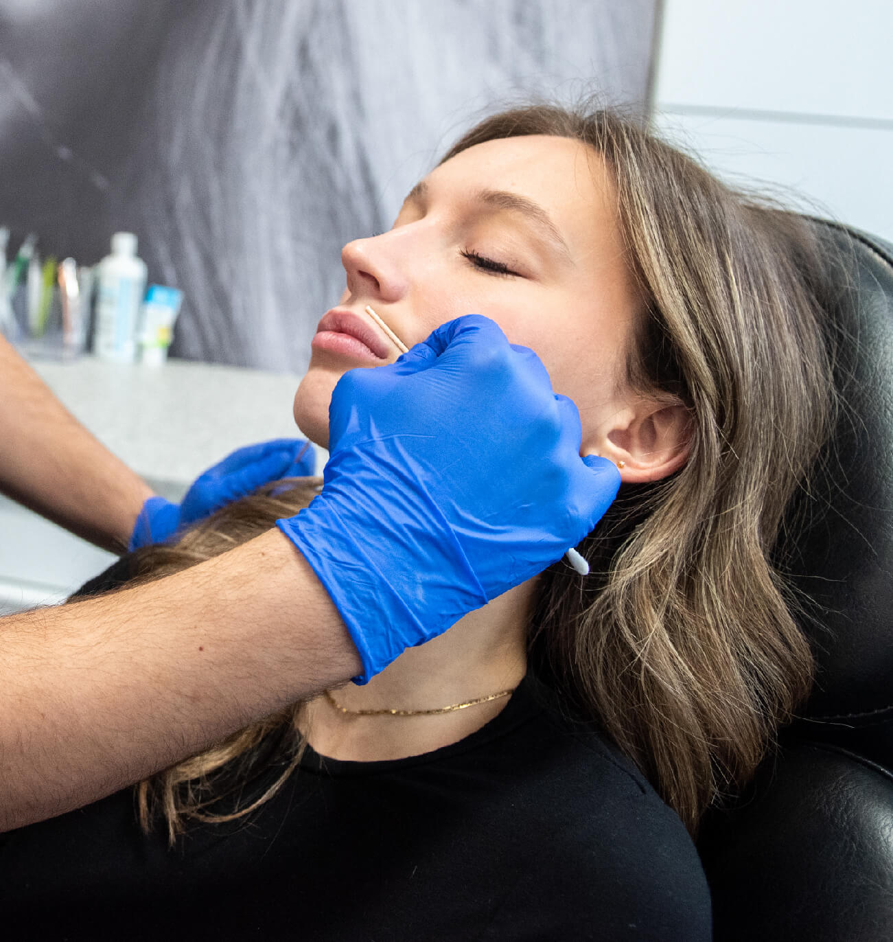 Consultation gratuite en médecine esthétique avec injection d’acide hyaluronique pour des lèvres volumisées, réalisée par un professionnel avec gants bleus.